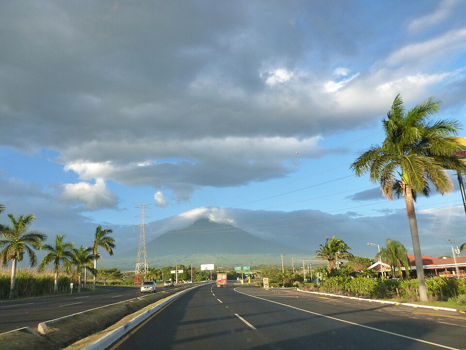 Carretera de Palín bordeada de palmeras, con el volcán al fondo